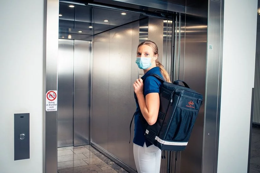 Frau mit Hausbesuchsrucksack im Einsatz im Fahrstuhl